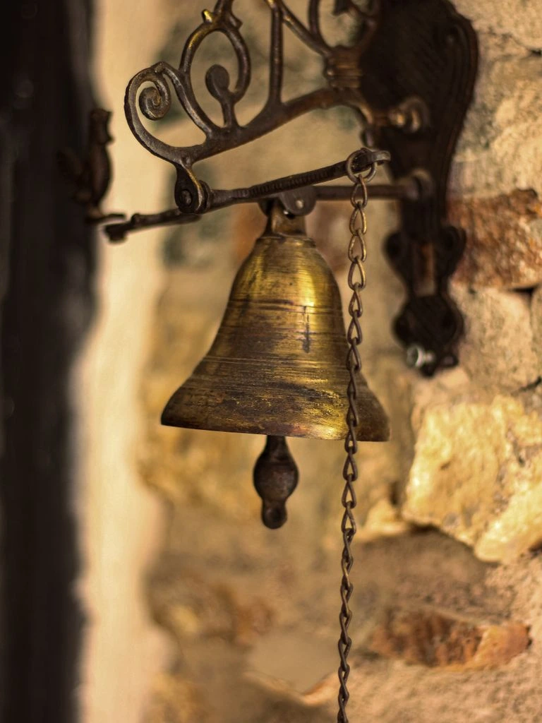 The brass bell beside the mahogany door at the entrance to the showroom.
