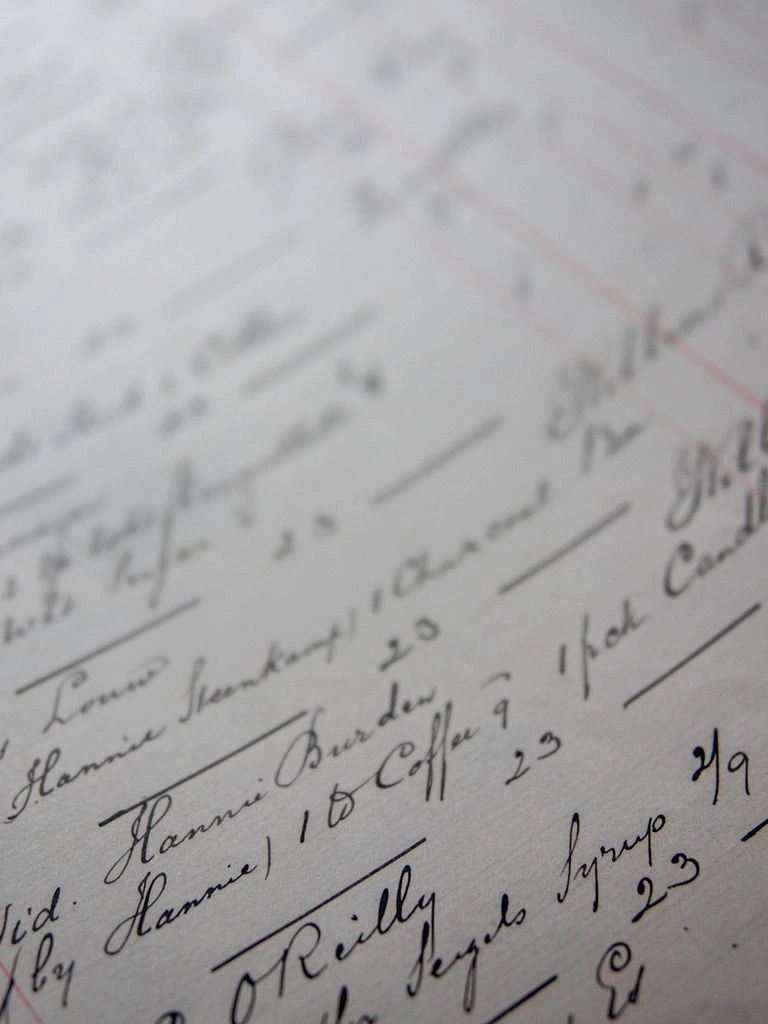 An open consignment ledger, handwritten in faded brown ink, with a fountain pen across the page.